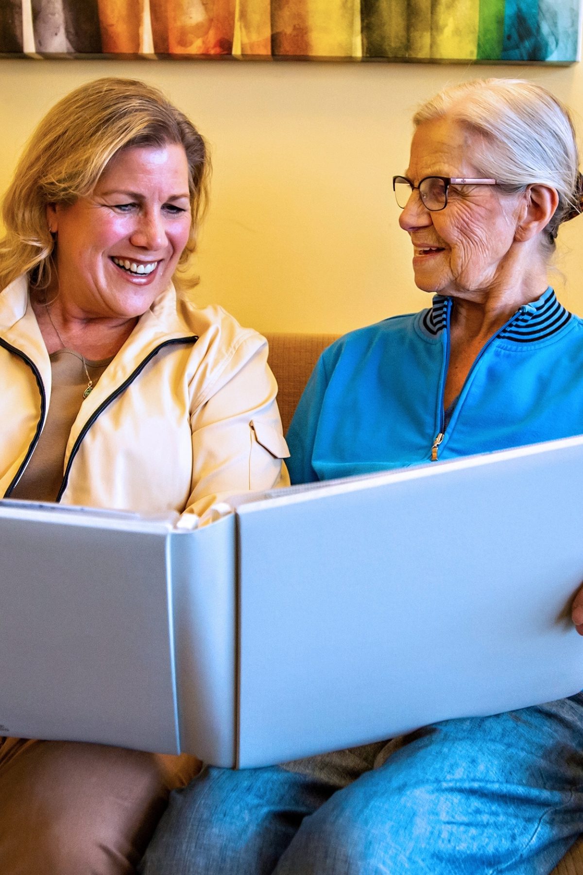 Someren Glen Senior Living Community in Centennial, CO - two women smiling as they look at photo album portrait